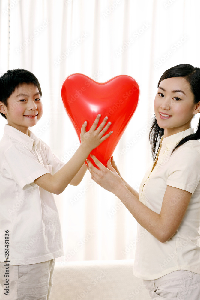 Woman and boy posing with a heart shaped balloon
