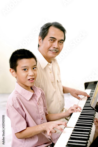 Senior man and boy playing the piano