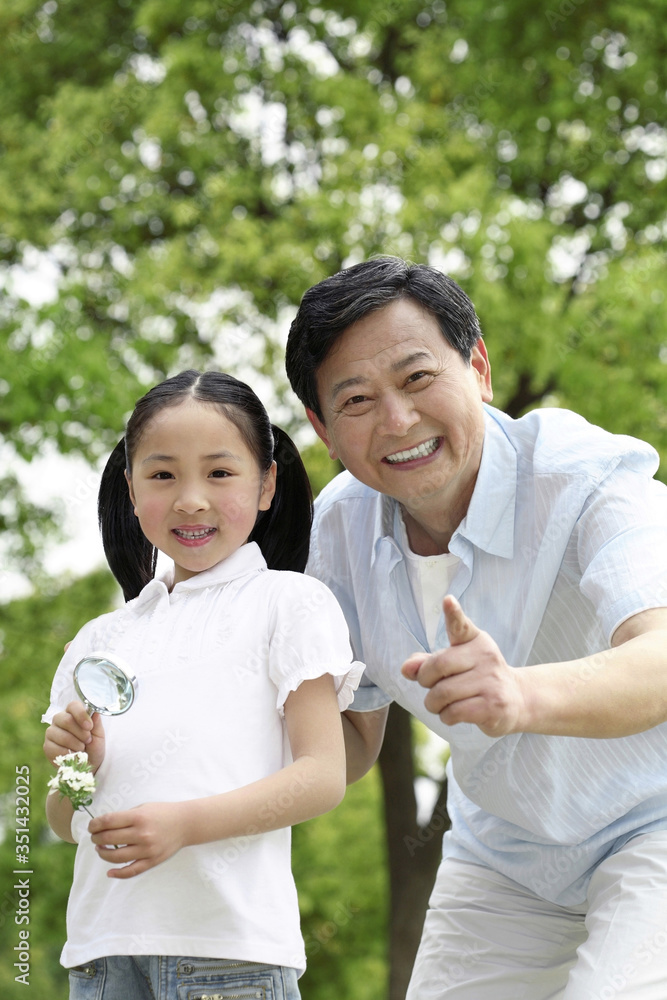 Senior man and girl with flowers and magnifying glass Senior man and girl with flowers and magnifying glass