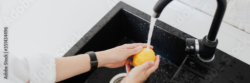 Εκτύπωση καμβά Woman rinsing a yellow lemon in a sink