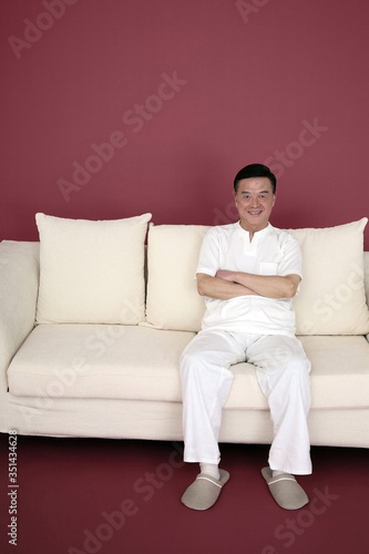 Senior man sitting on the couch, arms folded
