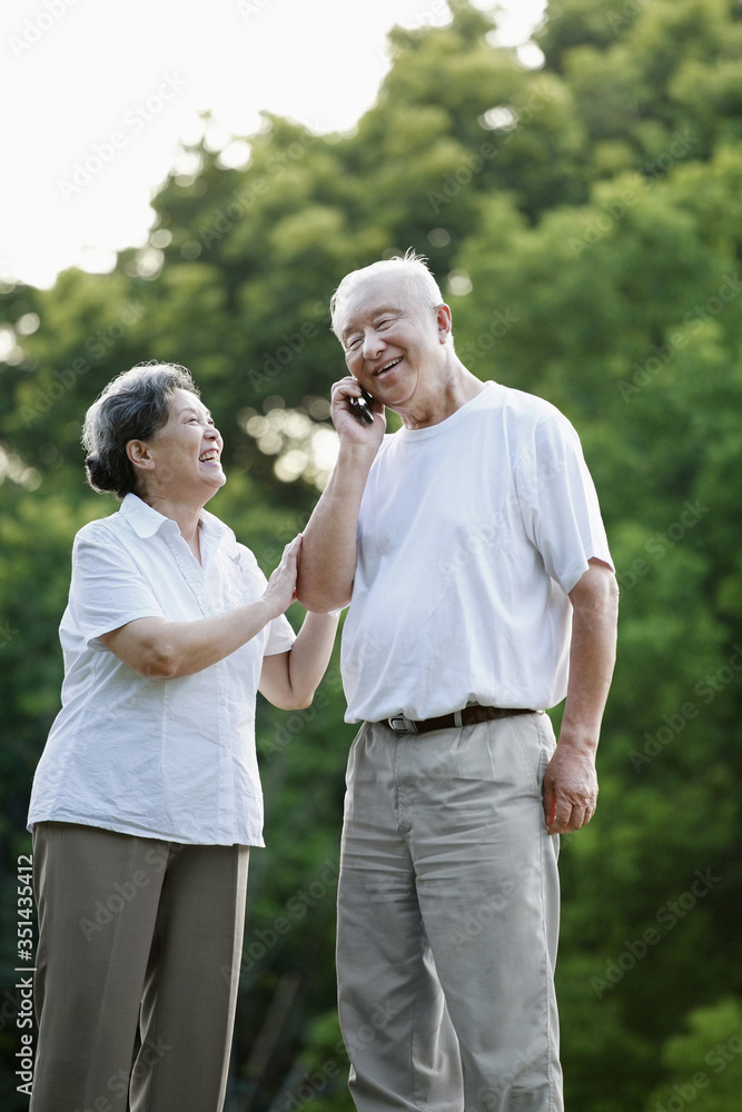 Senior woman laughing while senior man is talking on the phone