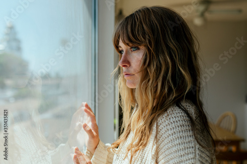 Sad woman staring out the window during a lockdown