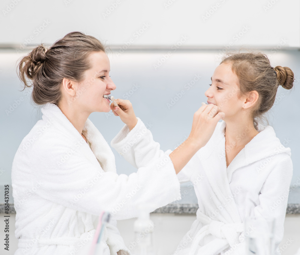 Happy mother and her daughter brush teeth each other's at home in morning Happy mother and her daughter brush teeth each other's at home in morning
