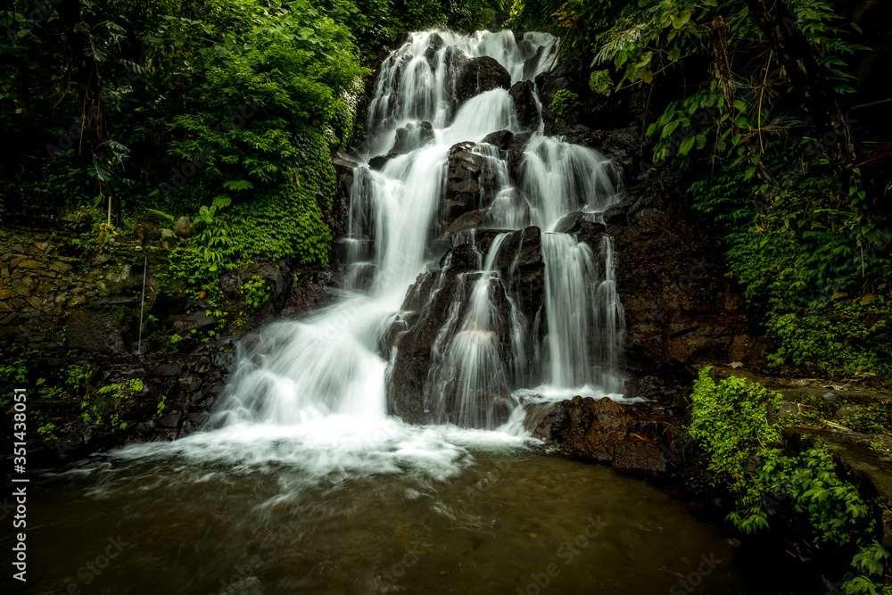Waterfall landscape. Beautiful hidden Jembong waterfall in tropical rainforest in Ambengan, Bali. Slow shutter speed, motion photography. Waterfall landscape. Beautiful hidden Jembong waterfall in tropical rainforest in Ambengan, Bali. Slow shutter speed, motion photography.