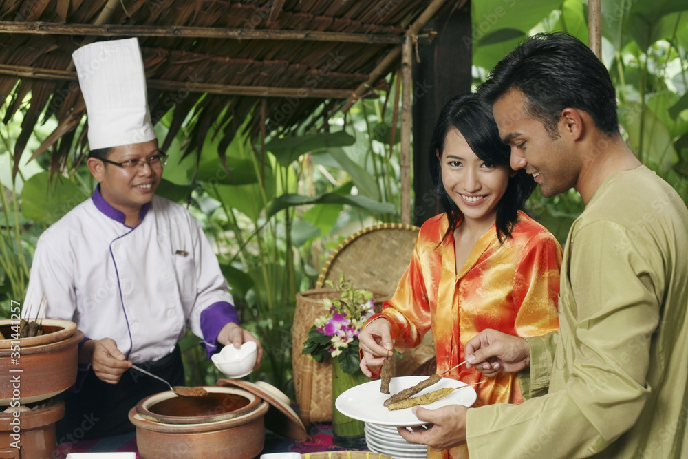 Man and woman taking satay from the stall Man and woman taking satay from the stall