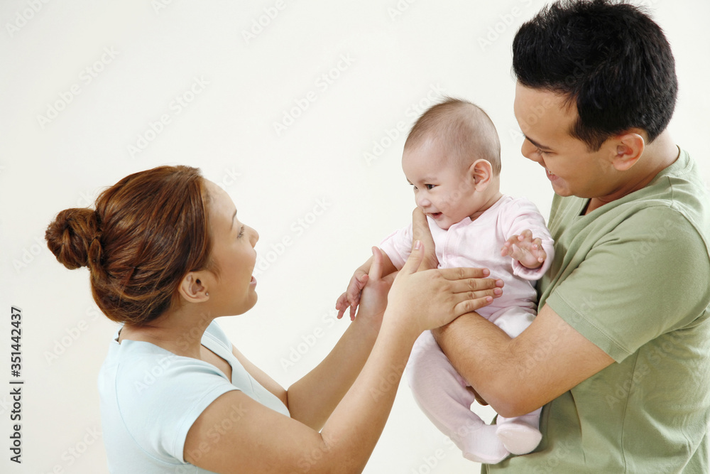 Man carrying baby, woman playing with the baby Man carrying baby, woman playing with the baby