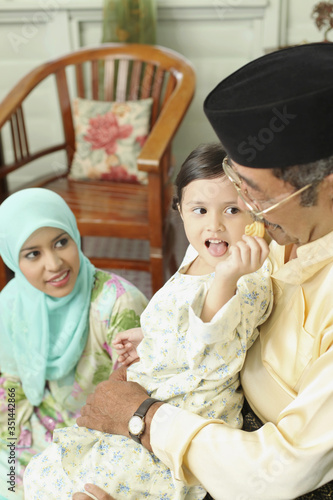 Girl feeding senior man with cookie, woman watching photo