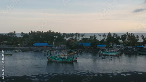 camera fly away from large boats and small fishing boats are separated by a water ridge Prancak Perancak west bali