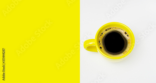 yellow cup of coffee on a double yellow and white background. Minimalism. The concept of morning coffee, breakfast.Copy space. top view