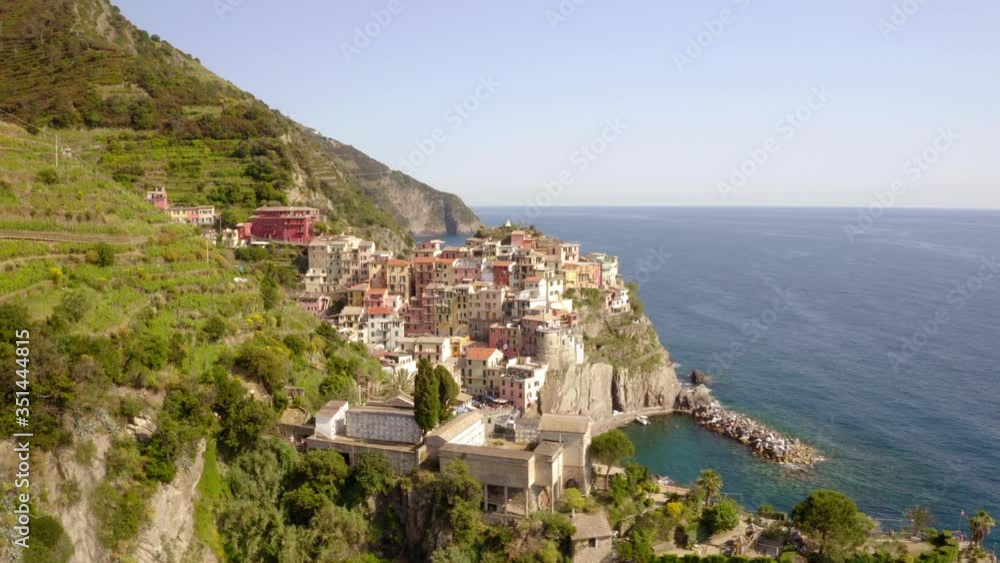 Aerial shot of coastal city on cliff near sea against sky, drone panning from left to right over buildings on sunny day - Cinque Terre, Italy Aerial shot of coastal city on cliff near sea against sky, drone panning from left to right over buildings on sunny day - Cinque Terre, Italy