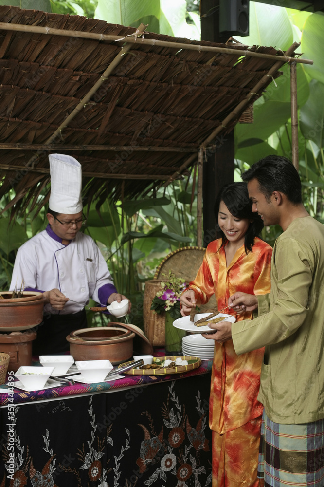 Man and woman taking satay from the stall Man and woman taking satay from the stall