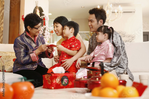 Couple and children getting red packet from senior woman