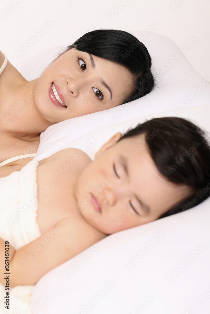 Woman looking at baby girl asleep beside her Woman looking at baby girl asleep beside her