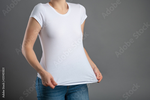 image of a young hipster girl in blank white t-shirt and blue jeans, mock up blank white t-shirt, gray background, isolate