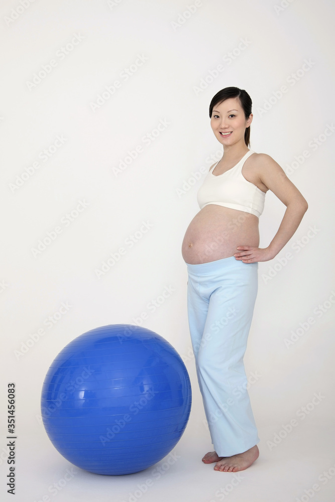 Pregnant woman standing beside fitness ball Pregnant woman standing beside fitness ball