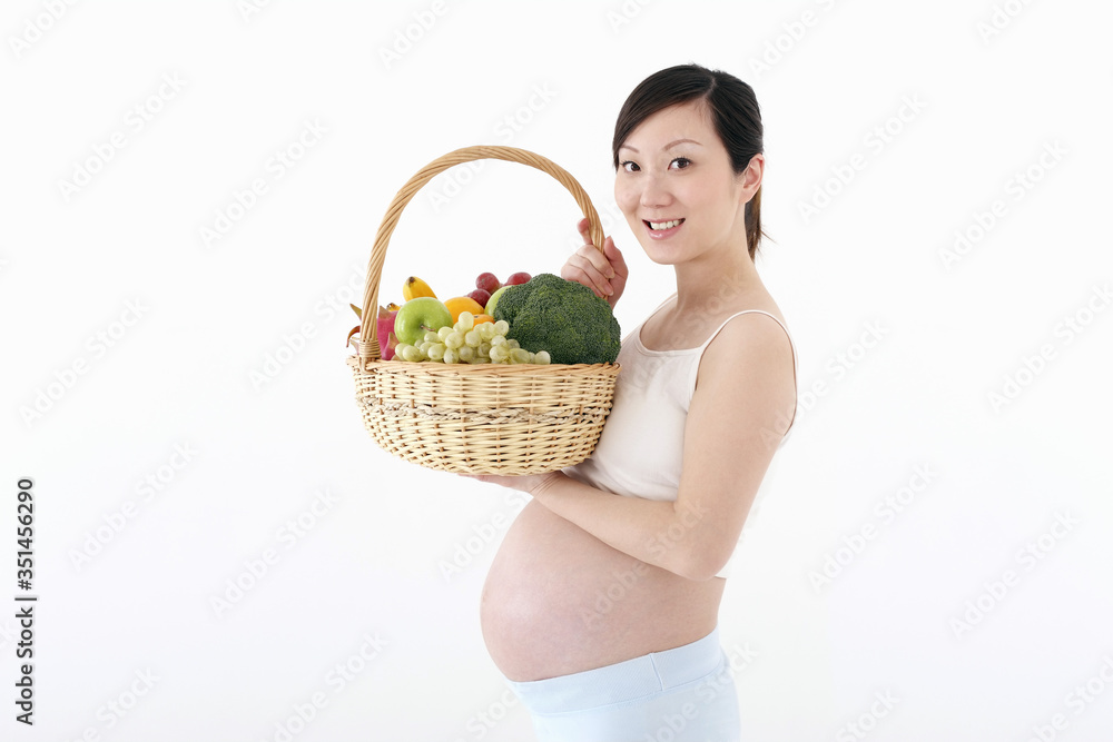 Pregnant woman holding a basket of fruits and vegetables Pregnant woman holding a basket of fruits and vegetables