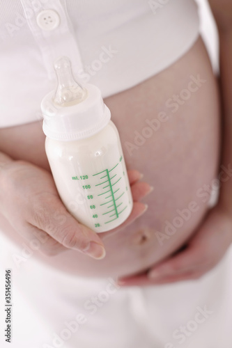 Pregnant woman holding baby bottle with milk