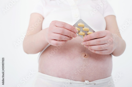 Pregnant woman taking supplement from blister pack