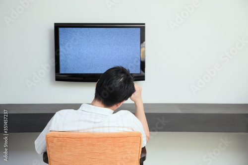 Man looking at ruined television with his hand on the head
