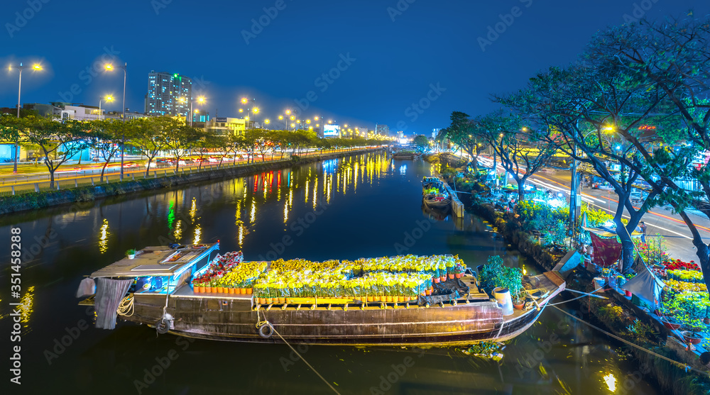 Flower boats full of flowers parked along canal wharf in sunset, a place for bustling flower market trade lunar new year in Ho Chi Minh City, Vietnam