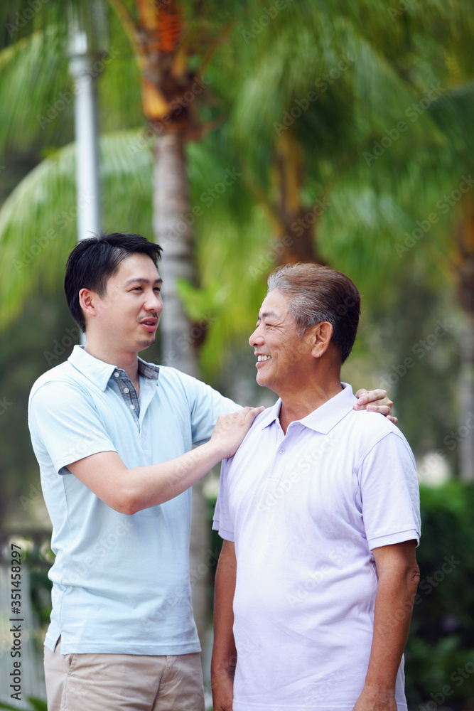 Man giving his father a pat on the shoulder while talking Man giving his father a pat on the shoulder while talking