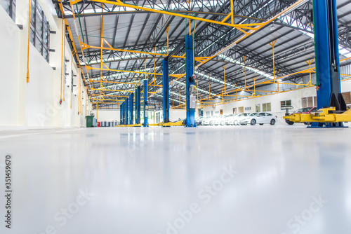 Fototapeta The interior decoration is an epoxy floor of an industrial building or a large automobile repair center with a steel roof structure that is built in an industrial factory