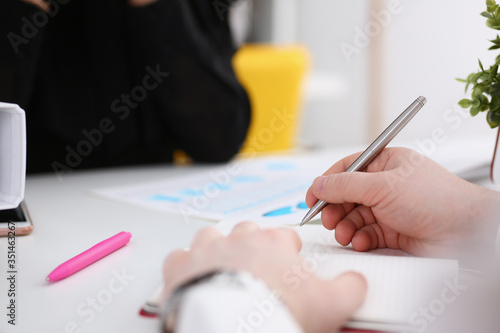 Group of people hold silver pen ready to make note