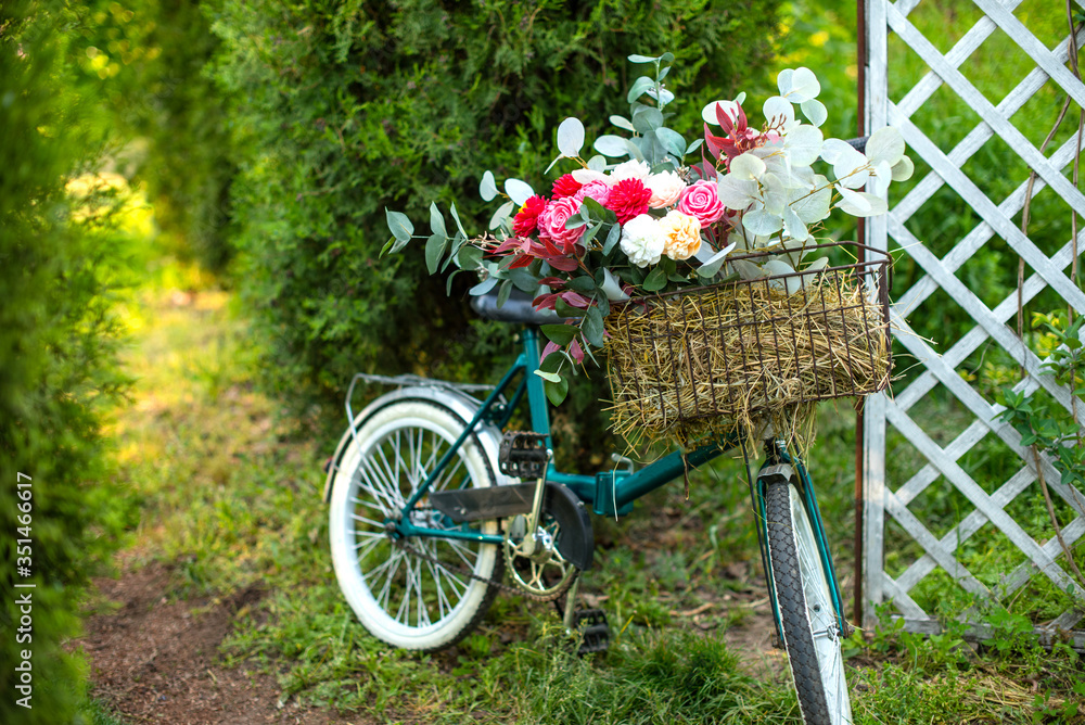 Beautiful bicycle with flowers in a basket stands on an avenue