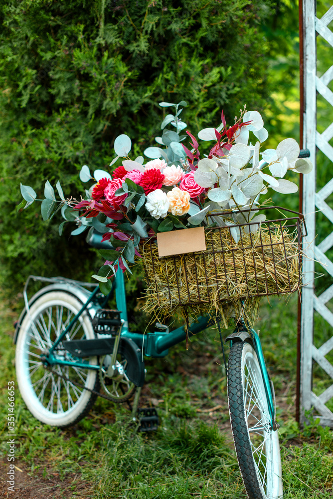 Beautiful bicycle with flowers in a basket stands on an avenue