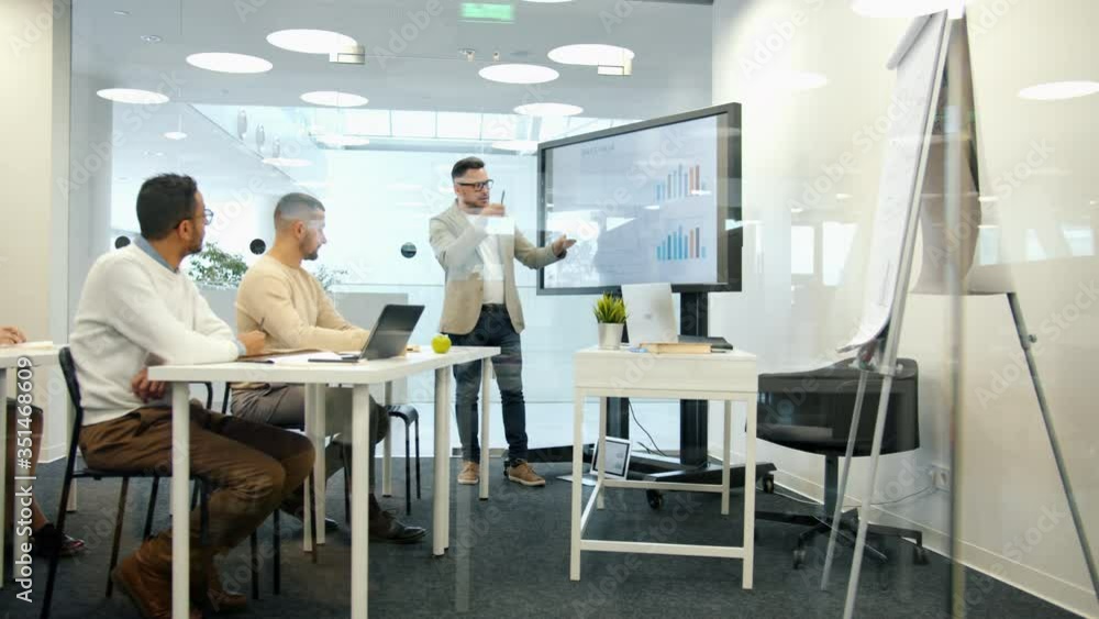 Boss talking to staff in conference room giving lecture about finance and marketing using digital interactive whiteboard speaking and gesturing. Boss talking to staff in conference room giving lecture about finance and marketing using digital interactive whiteboard speaking and gesturing.