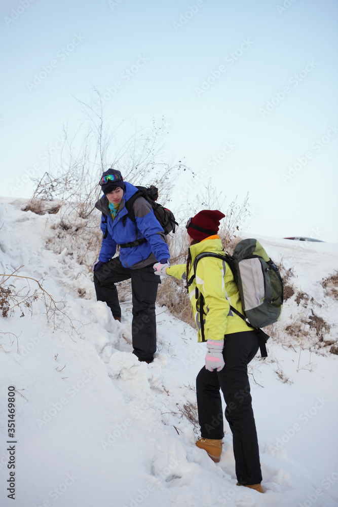 Man helping woman climbing up a steep snowy road