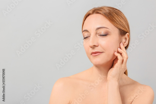 Mature woman on grey background. Plastic surgery concept