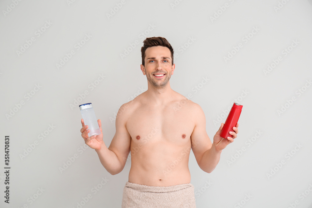 Fototapeta premium Handsome man with shower gels on light background