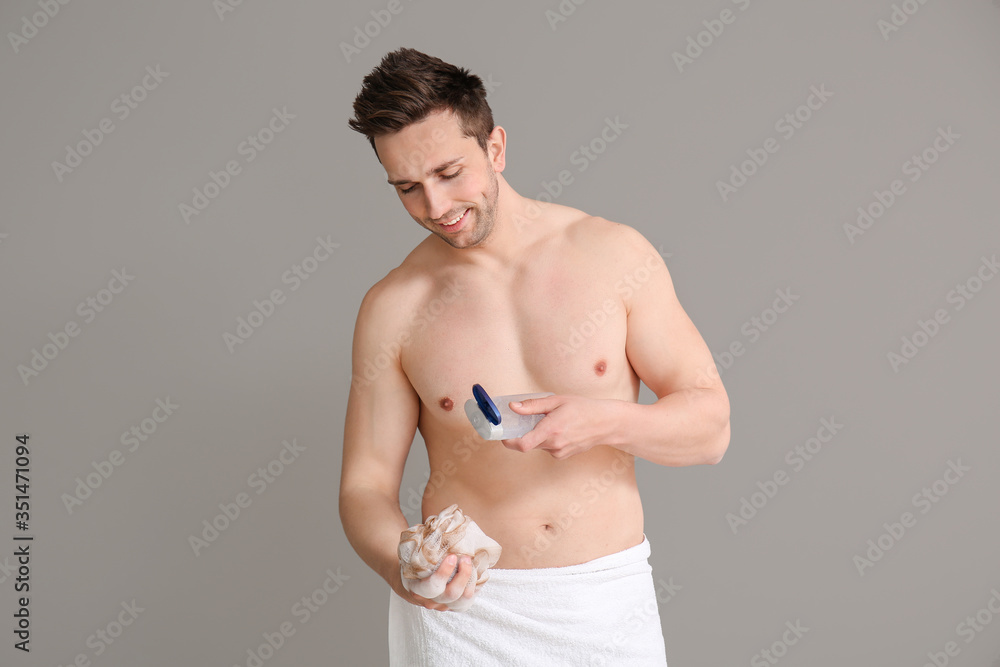 Handsome man with shower gel and loofah on grey background Handsome man with shower gel and loofah on grey background