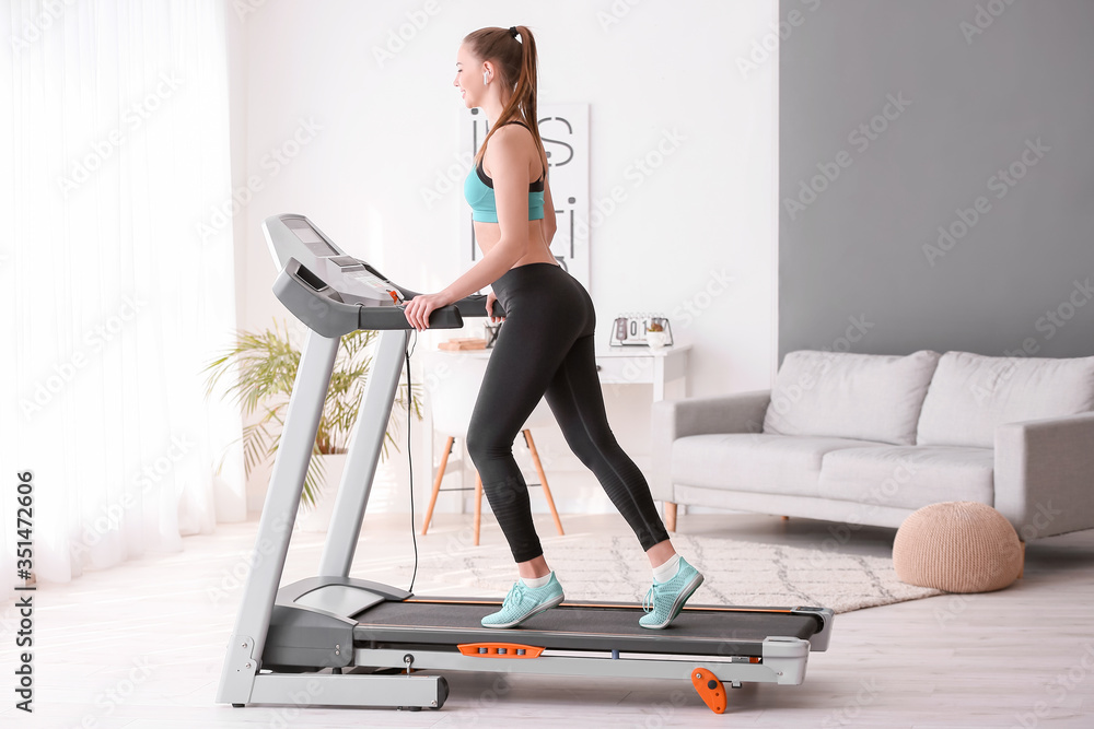 Sporty young woman training on treadmill at home - obrazy, fototapety, plakaty 