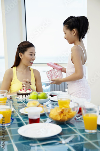 Girl giving her mother a surprise gift
