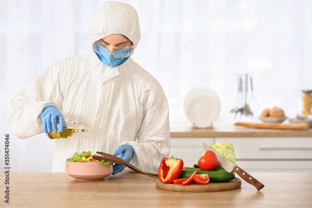 Woman in biohazard suit cooking in kitchen Woman in biohazard suit cooking in kitchen