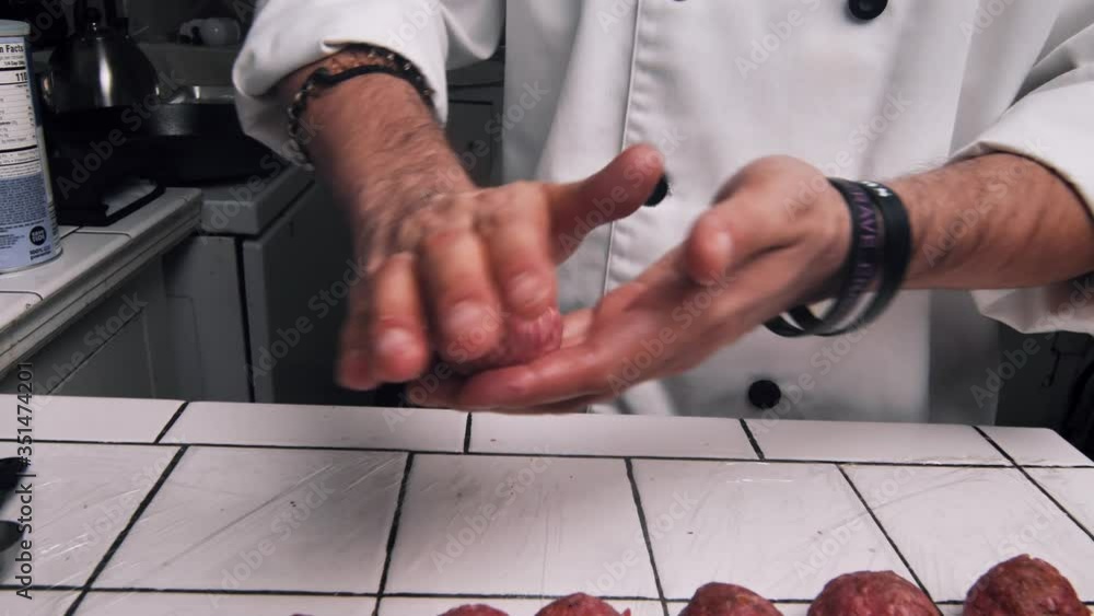 Male Caucasian hands role meatball between fingers into circular shape ...