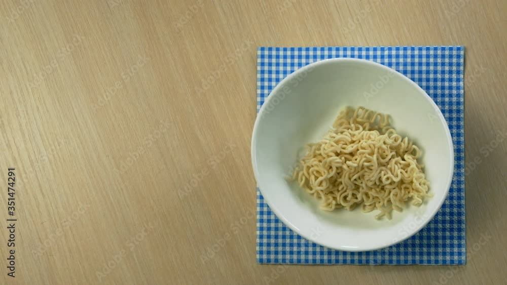 Noodles are put on white plate with kitchen tongs, poured spicy tomato sauce with chicken breast, sprinkle spices and garnished with half of boiled egg. Top-down food. Close up. Indoor. Noodles are put on white plate with kitchen tongs, poured spicy tomato sauce with chicken breast, sprinkle spices and garnished with half of boiled egg. Top-down food. Close up. Indoor.