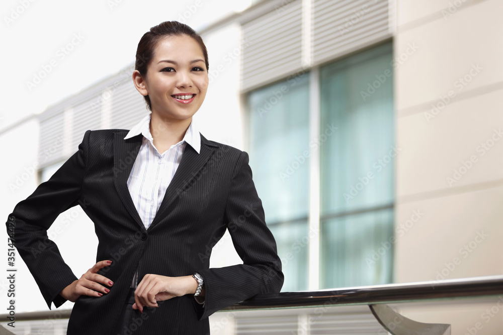 Businesswoman smiling and leaning on metal railing