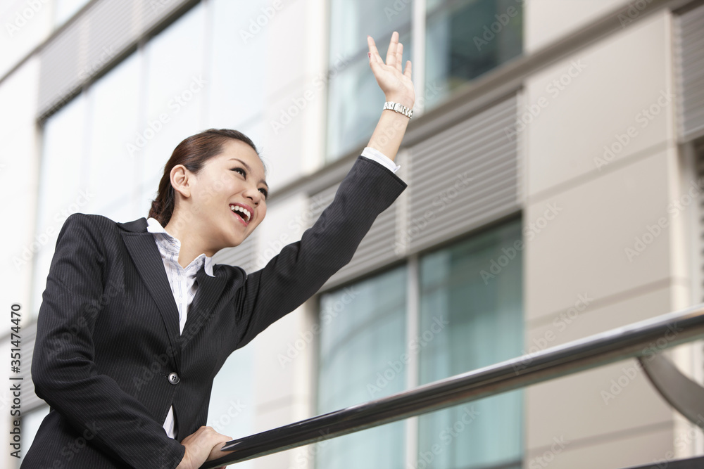 Businesswoman smiling and raising her hand