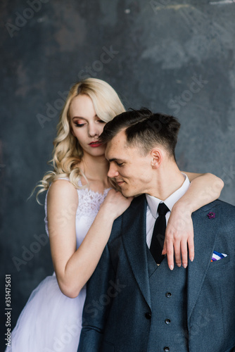 Beautiful wedding couple. Luxurious dress of the bride and stylish suit of the groom, studio photo shoot.