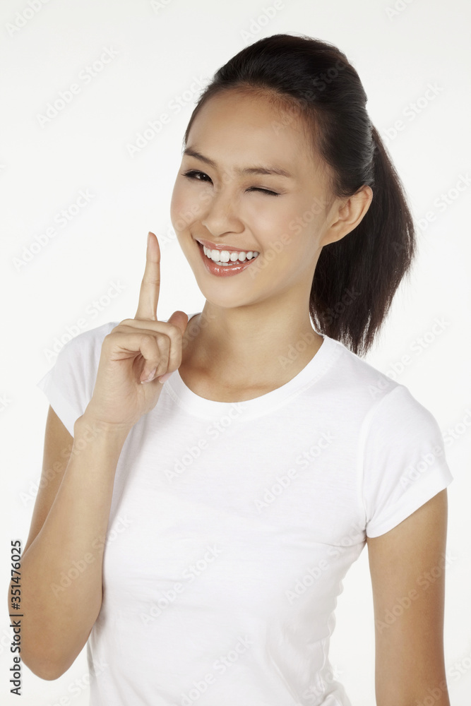 Happy woman showing index finger and winking at the camera Happy woman showing index finger and winking at the camera