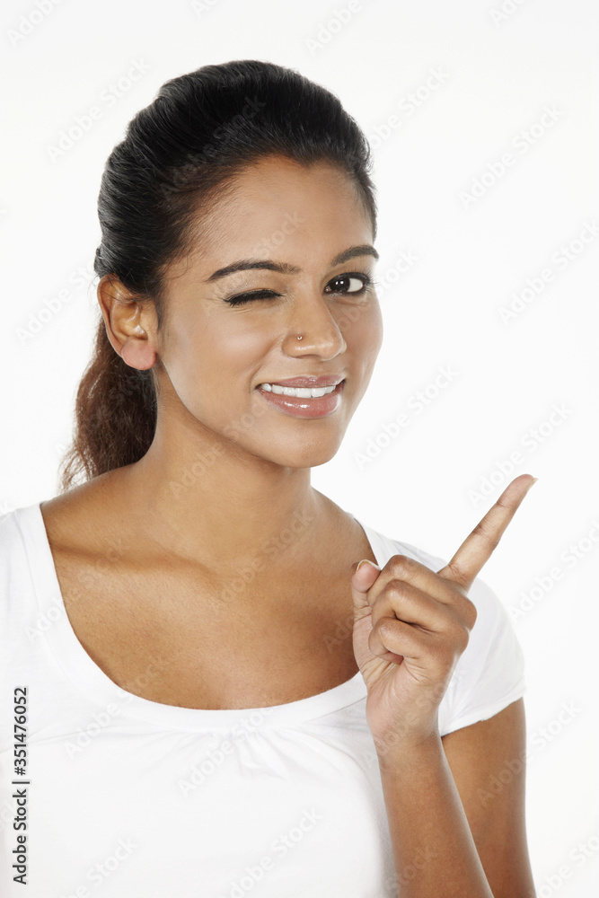 Happy woman showing index finger and winking at the camera Happy woman showing index finger and winking at the camera