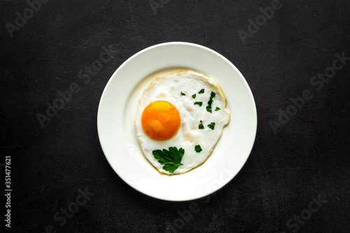 Fried eggs on plate - black background top-down