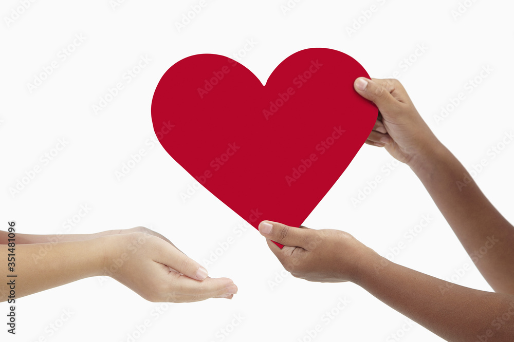 Girl giving a big cut out heart to her friend Girl giving a big cut out heart to her friend