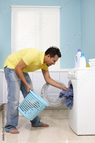 Man putting clothes into washing machine