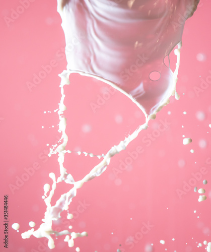 Splashes of white milk on a pink background.