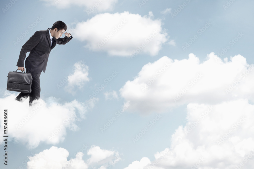 Young businessman standing on clouds, looking below Young businessman standing on clouds, looking below